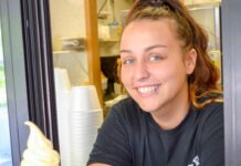 Smiling server at an ice cream stand in Muskegon serving sweet treats, highlighting family friendly restaurants and dessert spots