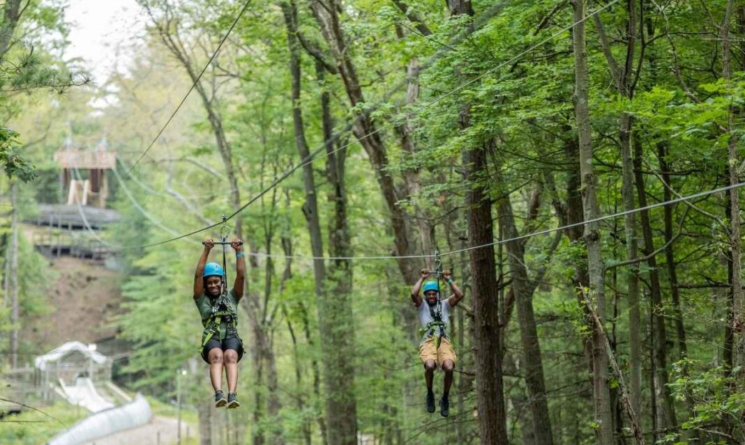 Kids ziplining through trees at Muskegon Luge Adventure Sports Park, a popular spring outdoor activity for families visiting Muskegon