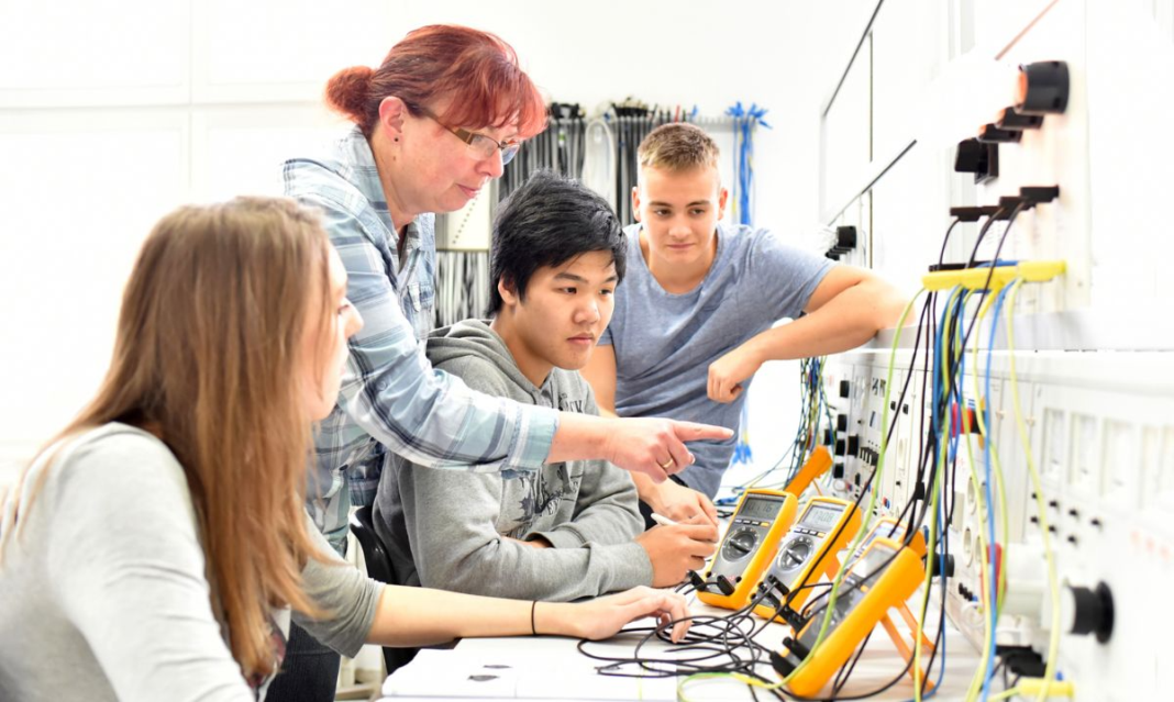 High school students learning electrical skills in a technical classroom with an instructor, gaining hands-on career training experience