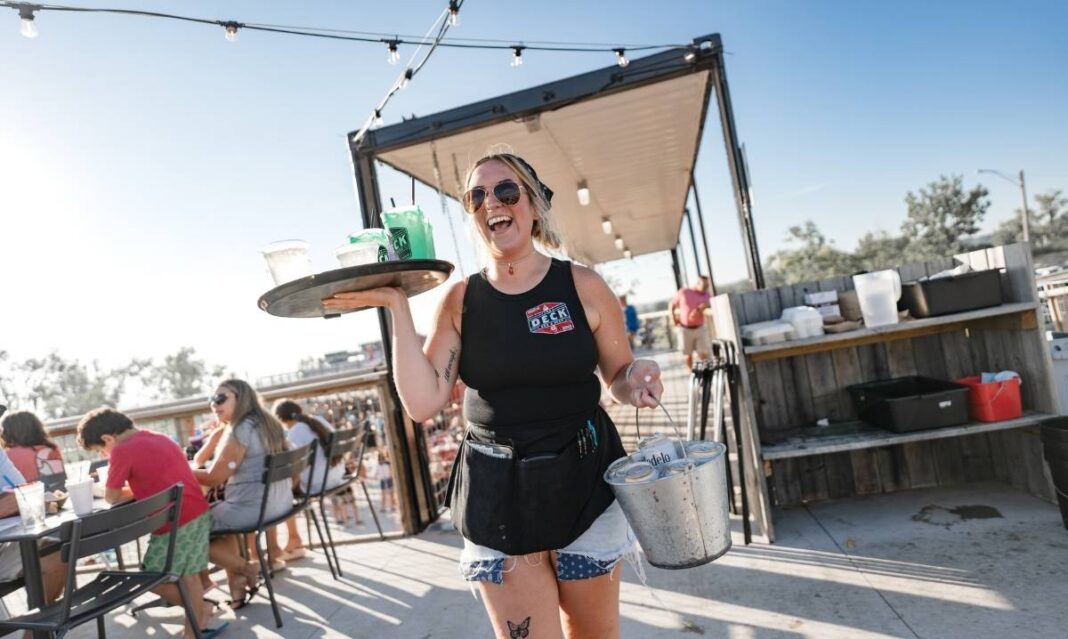 Server carrying drinks at The Deck in Muskegon, a lively lakeside spot for family friendly dining with outdoor seating and views