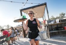 Server carrying drinks at The Deck in Muskegon, a lively lakeside spot for family friendly dining with outdoor seating and views